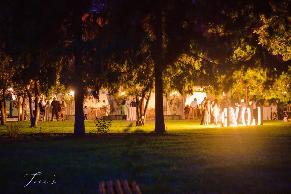 Grădina noaptea, sub copaci luminați, cu literele LOVE aprinse pe gazon